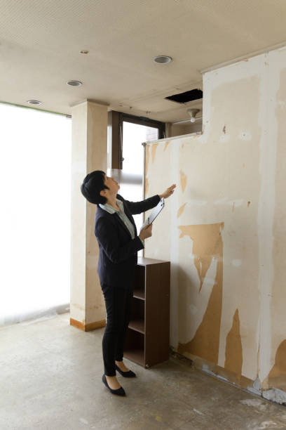 mid adult japanese businesswoman making clipboard notes in empty new office.